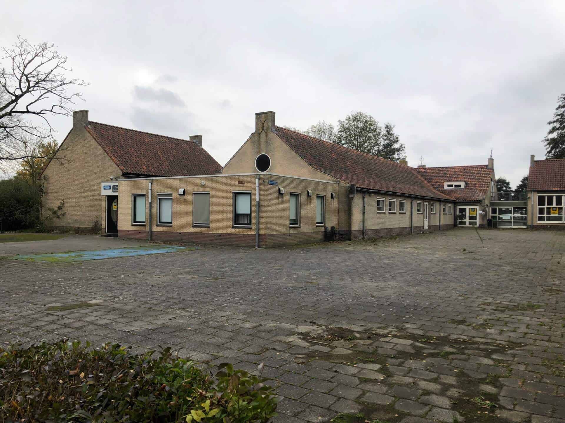 Achterzijde (gevoelsmatig de voorzijde) en schoolplein van de voormalige Zuiderbasisschool, met speelterrein en bakstenen gevels.