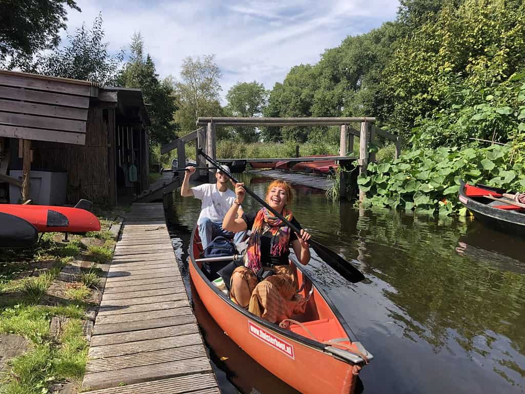 Twee kanoërs voor een houten brug in Giethoorn bij het startpunt voor kanotochten.